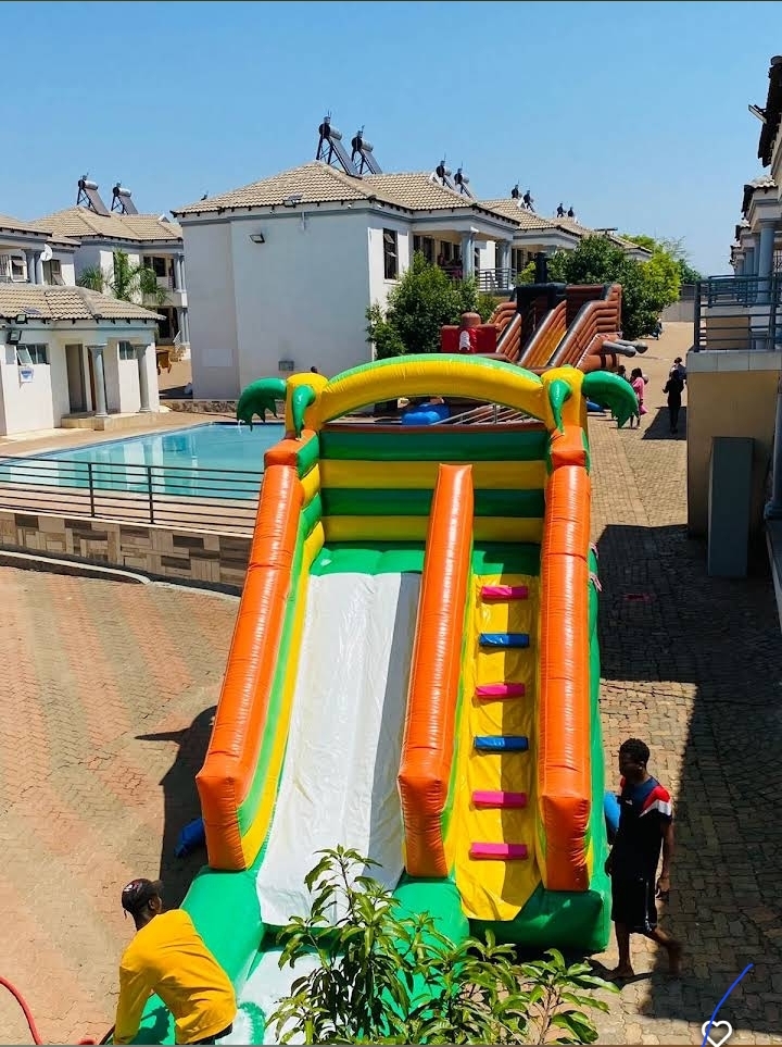 Inflatable water slide set up next to the pool during a student pool day at Muthathe Student Village